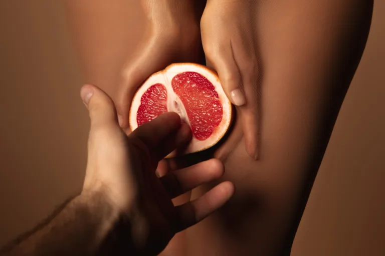 cropped view of man reaching woman in nylon tights holding grapefruit